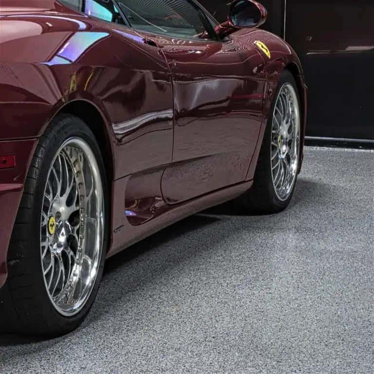 Red sports car parked on a gray flaked epoxy and polyaspartic coated floor.