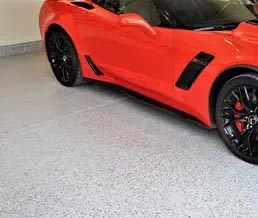 Red car parked on a garage floor coated with an epoxy primer and polyaspartic topcoats.