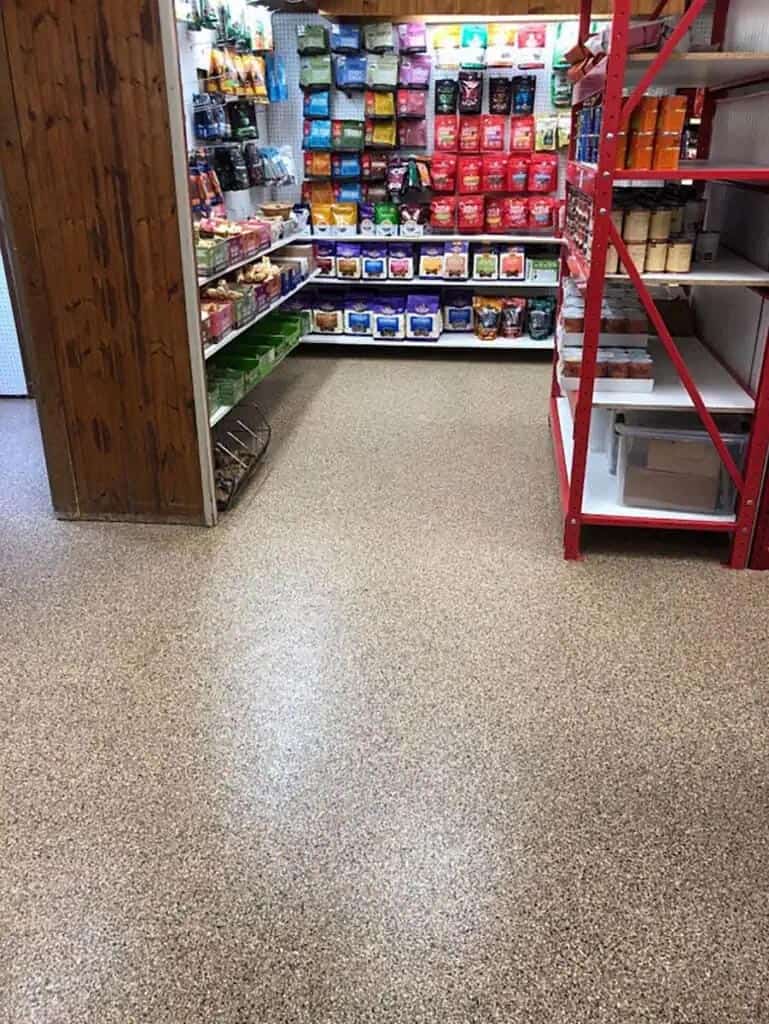 Shelving stocked with food items sits atop a beautiful full flake epoxy floor.